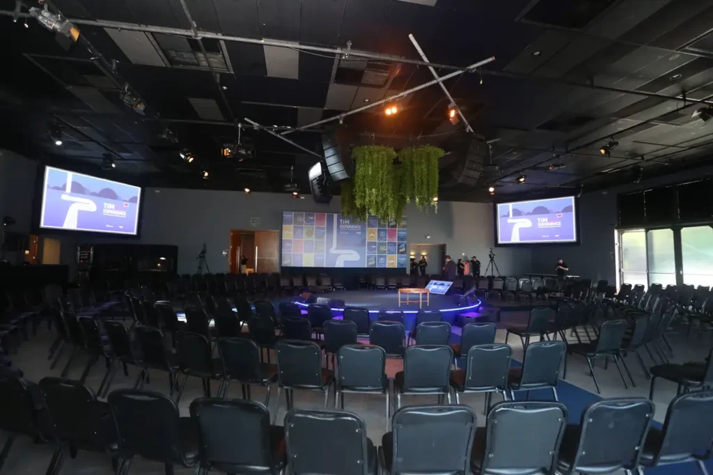 Guia Completo: Como Planejar Eventos Corporativos de Impacto Auditório com cadeiras dispostas em círculo ao redor de palco central iluminado